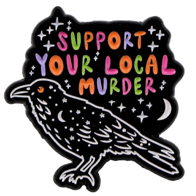 A stylized black raven with star-like dots appears under colorful “Support Your Local Murder” text, surrounded by stars, a crescent moon, and accented with a unique coffin badge from Kiss Me Later.